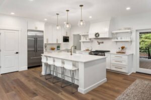 A bright, clean white kitchen featuring a spacious center island for cooking and dining.