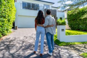 A couple stands in front of their house, discussing plans for home remodeling. 