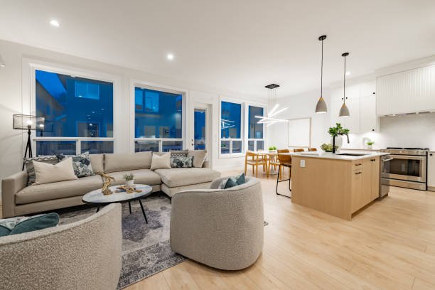 A modern living room featuring hardwood floors and large windows, showcasing a luxury home remodeling.