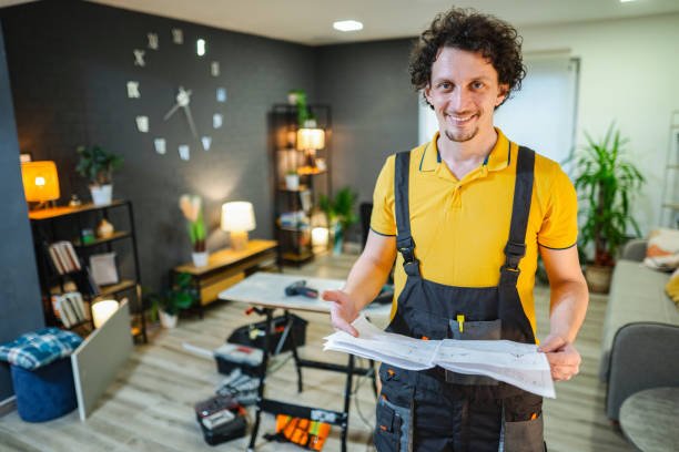 A man in overalls is holding a piece of paper, which may contain information about home remodeling near me.